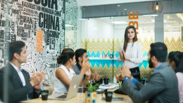A conference room with a young woman leading the discussion